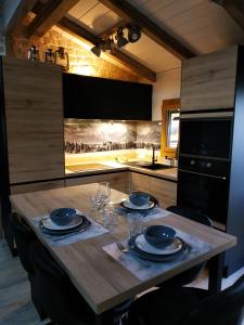 una cucina con tavolo in legno, piatti e bicchieri di Chalet de charme entre Genève, Annecy et stations a Viuz-en-Sallaz