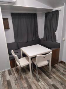 a white table and chairs in a small room with a couch at Mobile home Portiragnes in Portiragnes +2 photos