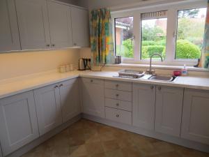 a kitchen with white cabinets and a sink and a window at Harecroft in Hunstanton