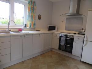 a kitchen with white cabinets and a sink and a refrigerator at Harecroft in Hunstanton