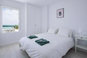 a white bedroom with a white bed and a window at Dulce Barrosa Mar Beach Front in Chiclana de la Frontera