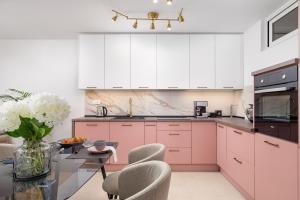 uma cozinha com armários cor-de-rosa e uma mesa com cadeiras em Seaview apartment „Megan“ with sunny terrace em Kastav