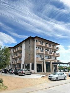 a building with cars parked in a parking lot at Siesta Srebrno Jezero in Veliko Gradište