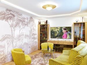 uma sala de estar com televisão e cadeiras amarelas em Gasthof Hametner mit Innviertlerhof mit direktem Zugang zur Therme Mediterrana durch unseren Garten! em Bad Hall