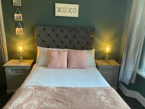 een slaapkamer met een bed met roze kussens en 2 lampen bij Inn Cardiff in Cardiff