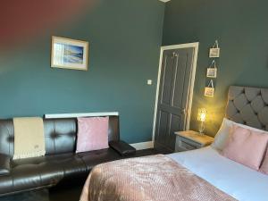 a bedroom with a bed and a leather couch at Inn Cardiff in Cardiff