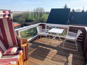 ein Balkon mit Tisch und Stühlen auf einem Dach in der Unterkunft Unser Haus am Deich Wohnung Meerblick in Nordstrand