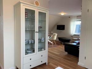 a white cabinet with glass doors in a living room at Unser Haus am Deich - Wohnung Meerblick in Nordstrand