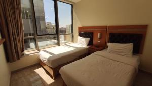 a hotel room with two beds and a large window at Jawharet Alswefiah Hotel Suites in Amman