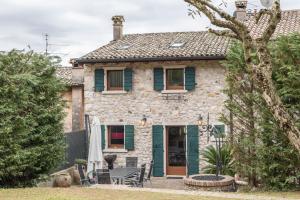 ein Steinhaus mit grünen Rollläden und einer Terrasse in der Unterkunft Casa Rustico in Costermano sul Garda