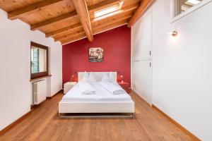 sypialnia z białym łóżkiem i czerwoną ścianą w obiekcie Casa Rustico w mieście Costermano
