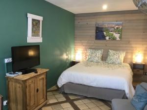 a bedroom with a bed and a flat screen tv at La Cambra dé Monflanquin in Monflanquin