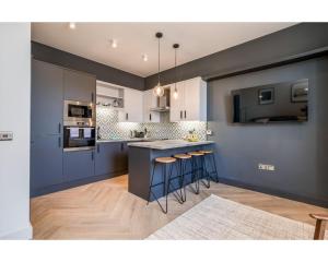 cocina con paredes azules y encimera con taburetes en Central Belfast Apartments: University Street, en Belfast