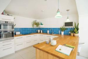 a kitchen with white cabinets and a wooden counter top at Seashells - Bembridge in Bembridge