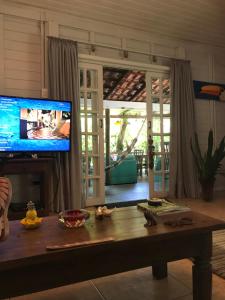 sala de estar con mesa y TV en Pousada das Gêmeas en Ilha do Mel