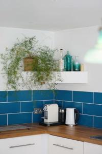 a kitchen with blue tiled walls and a counter with a toaster at Seashells - Bembridge in Bembridge