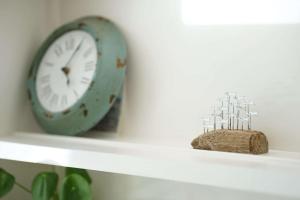 a clock sitting on a shelf next to a rock at Seashells - Bembridge in Bembridge