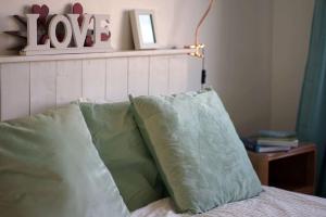 a bed with green pillows and a shelf with a love sign at Seashells - Bembridge in Bembridge