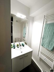 y baño con lavabo blanco y espejo. en Neoresid Paris-Gagny en Gagny