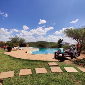 two people sitting on a bench near a swimming pool at Oldonyo Orok Lodge in Kajiado