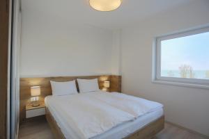 a bedroom with a large white bed with a window at Admiral Luxury III Apartman By BLTN in Siófok