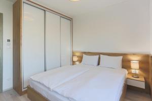 1 dormitorio con 1 cama grande con sábanas blancas en Admiral Luxury III Apartman By BLTN en Siófok