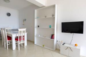 a white living room with a table and a tv at Duka's House in Lukovë