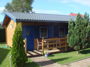 a blue cabin with a wooden deck in a yard at WIR Gąski - domki letniskowe in Gąski