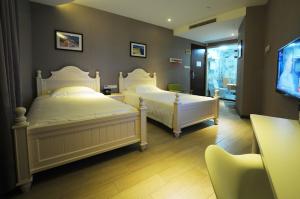 two white beds in a room with a tv at Shanghai Chi Chen Boutique Hotel in Shanghai