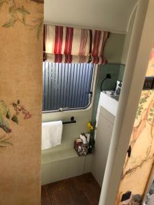 een kleine badkamer met een raam en een wastafel bij Down The Garden Path Vintage Caravan B&B , Hennock in Newton Abbot