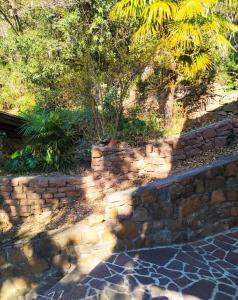 un mur de retenue en pierre avec une clôture en pierre et des arbres dans l'établissement TORRE GARDEN HOME - casa singola nella città di Bolzano con giardino privato, à Bolzano