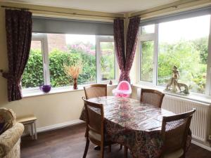 a dining room with a table and chairs and windows at Rowan House in Hunstanton