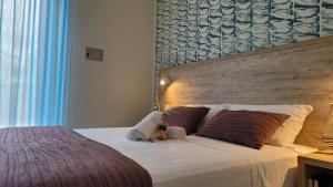 a teddy bear sitting on top of a bed at Hotel Adigrat in Riccione