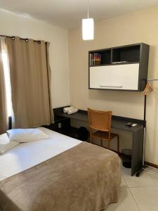 a bedroom with a bed and a desk and a chair at COMFORT DUPLEX in Rio das Ostras