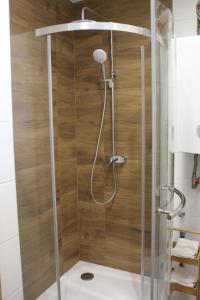 a shower in a bathroom with a wooden wall at Apartamenty Przy Deptaku w Radomiu in Radom