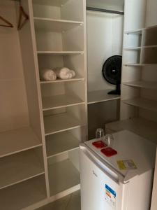 a small kitchen with a refrigerator and shelves at COMFORT DUPLEX in Rio das Ostras