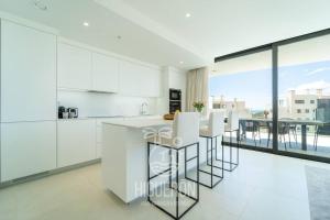 a kitchen with white cabinets and a table with stools at HigueronRentals The Palm in Málaga