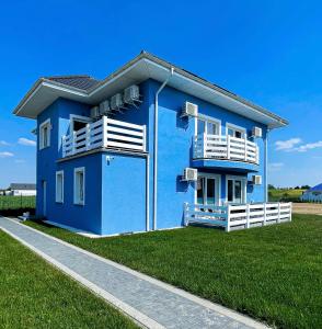een blauw huis met een balkon en een grasveld bij Willa Azul - Podgrzewany basen, klimatyzacja w całym obiekcie in Sarbinowo