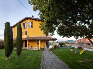 una casa amarilla con césped y árboles en B&B La Canfora en Atri