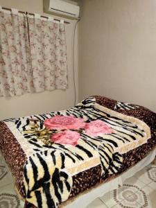 a bed with a zebra blanket with pink roses on it at Alvar Nuñez in Puerto Iguazú