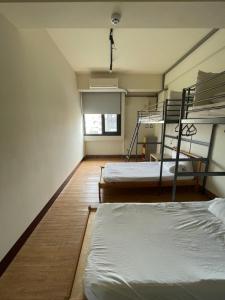 Chiayi Petite Hostel في مدينة تشيايي: غرفة بسريرين بطابقين ونافذة