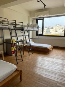 a room with three bunk beds and a large window at Chiayi Petite Hostel in Chiayi City