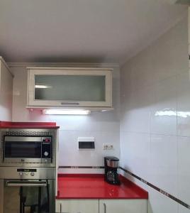 kuchnia z kuchenką mikrofalową i czerwonym blatem w obiekcie Apartamento Portugalete w mieście Portugalete