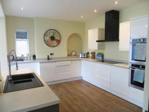 a kitchen with white cabinets and a clock on the wall at Seaside Retreat in Hunstanton