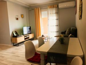un soggiorno con tavolo, sedie e TV di Diti's Apartment a Shkodër