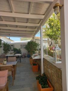 un patio con mesas y sillas y una pared de piedra. en Athina Guesthouse, en Hydra