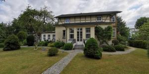 a large yellow house with a garden in front of it at Ferienwohnung in Heringsdorfer Villa Koje in Bansin