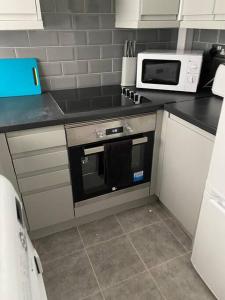 a kitchen with a stove and a microwave at Modern 2 bed sleep 5 close to Anfield Stadium in Liverpool