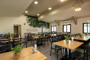 a dining room with wooden tables and chairs at Erettz Dafna Travel Hotel in Metsudat Menahem Ussishkin Alef