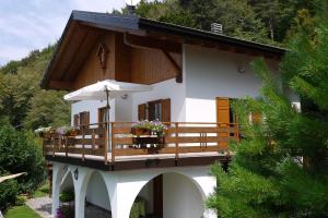 a house with a balcony with an umbrella at Chalet nel bosco con lago e panorama mozzafiato in Lagolo di Calavino